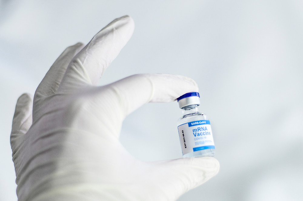 A gloved hand holding a vial of medicine.